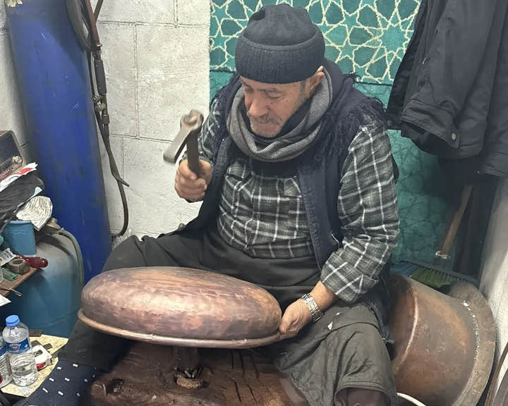 Mikdat Çelik treibt ein Kupferwaschbecken mit dem Hammer in seiner Werkstatt in Gaziantep